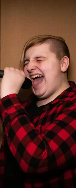 A singer in a red and black plaid shirt passionately performing into a microphone. A singer in a red and black plaid shirt passionately performing into a microphone.